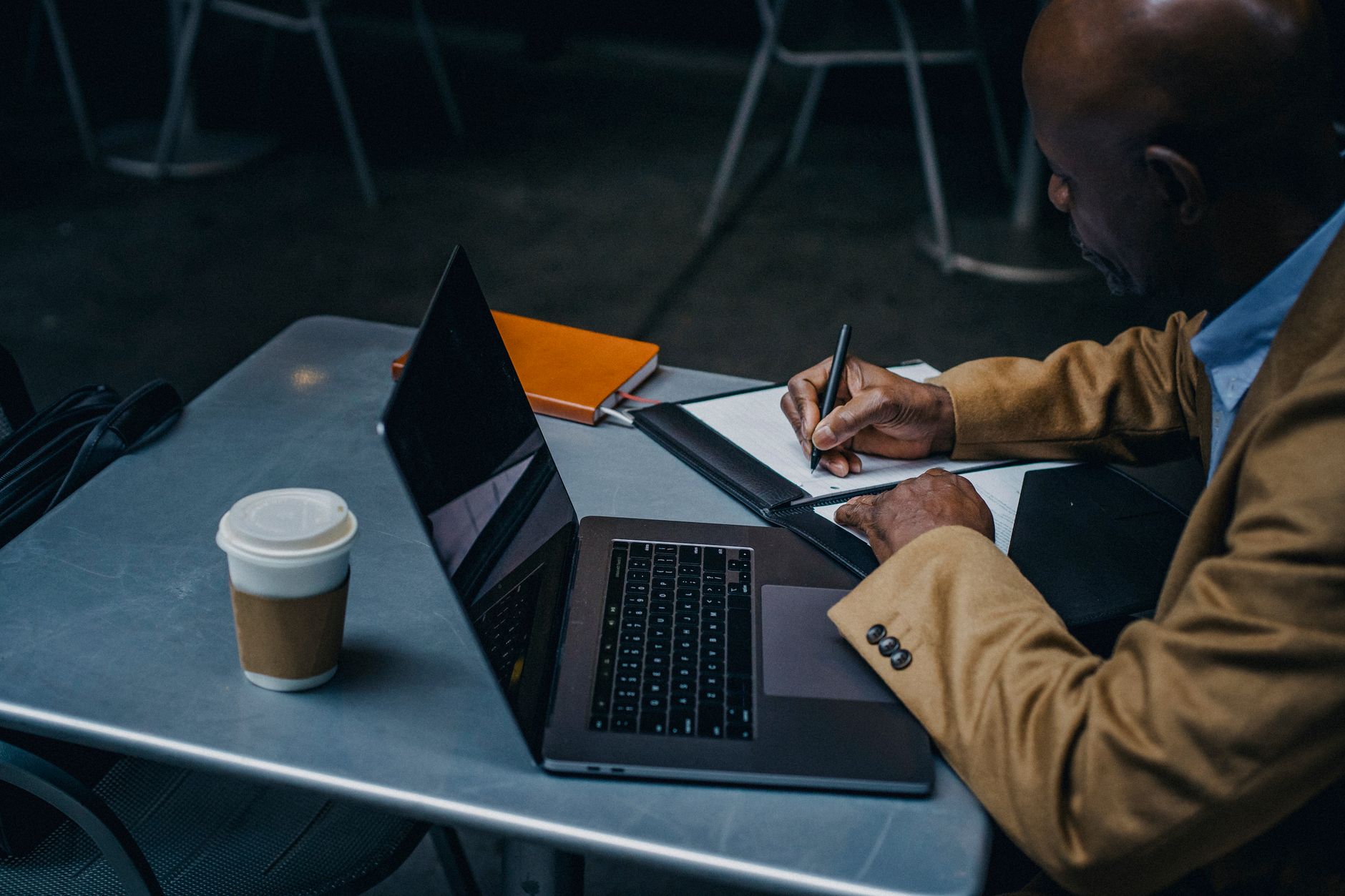 Czarnoskóry freelancer przy laptopie robi notatki do biznesplanu