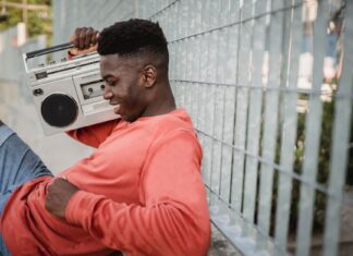 Muzyka hip‑hop i rap z USA jako okno na język ulicy i współczesne społeczeństwo Młody czarnoskóry mężczyzna słucha muzyki z kasetowego walkmana przy ogrodzeniu