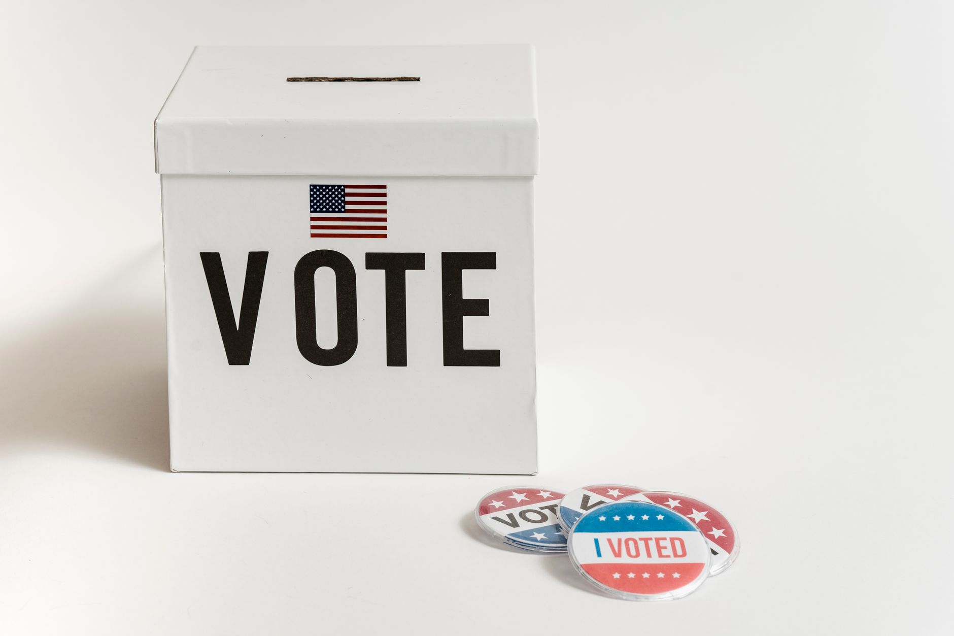 Biała urna wyborcza z flagą USA i przypinkami I Voted na tle białym