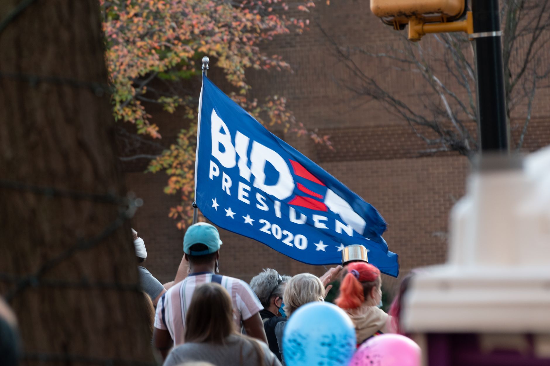 Różnorodny tłum na proteście z flagą Biden 2020 na zewnątrz
