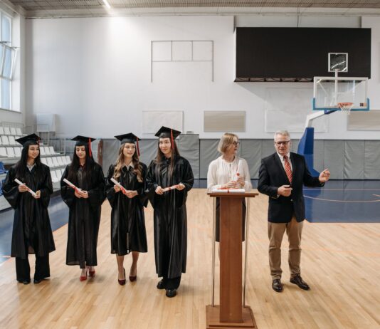 Stypendia sportowe i akademickie w USA dla Polaków: jak zdobyć dofinansowanie na studia? Absolwenci w togach odbierają dyplomy podczas uro