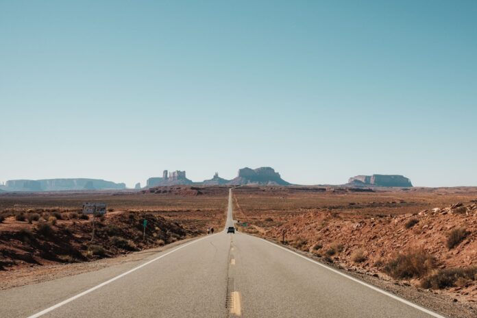 Malownicza droga prowadząca przez Monument Valley pod bezchmurnym niebem Malownicza droga prowadząca przez Monument Valley pod bezchmurnym niebem